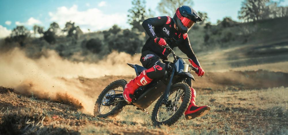 Crossförare sladdar i grusen med en svart enduro cross